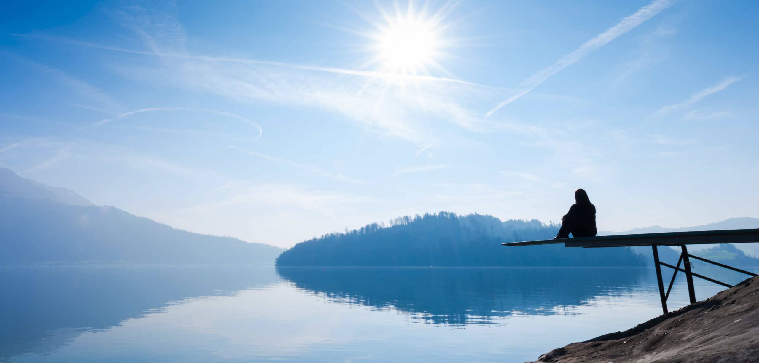 a Woman is sitting on the pier. blauer Himmel, blaues Wasser, Reflexion zum Jahresende