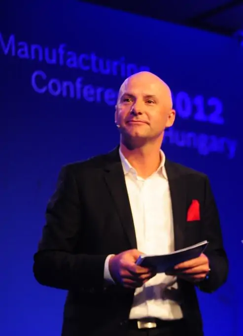 Keynote Speaker Arne Stoermer, Mann, Glatze, Sacko scharz, weißes Hemd, blauer Hintergrund, Bühne